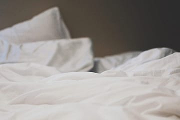 Ein leeres Bett mit weißen Laken.